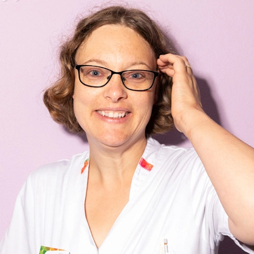 Zorgmedewerker met bril in wit uniform, werkzaam in de zorgsector