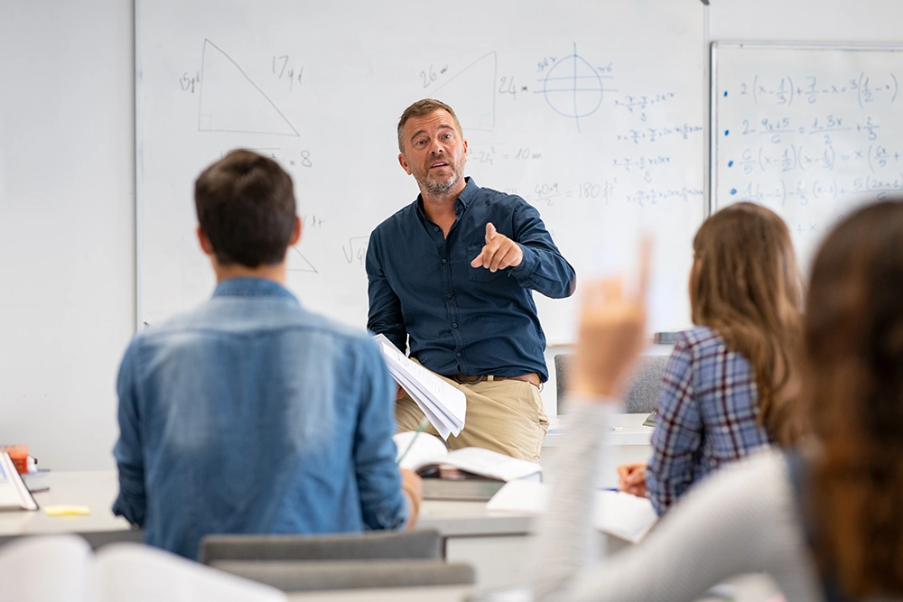Docent voor een whiteboard geeft les aan studenten in een klaslokaal