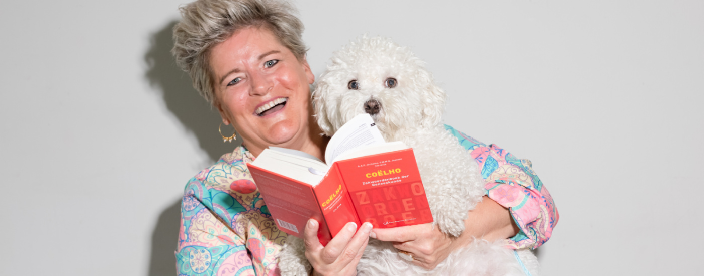 Vrouw met blond haar houdt een kleine witte hond en boek vast