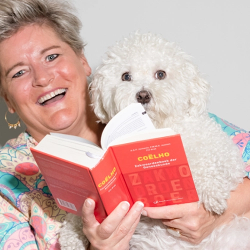 Vrouw met blond haar houdt een kleine witte hond en boek vast