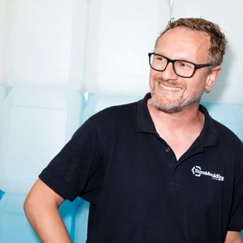 Lachende medewerker in zwart poloshirt tijdens werk bij Euromoldings