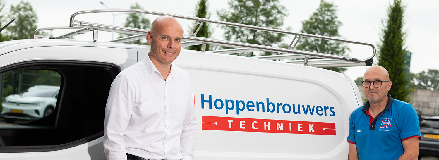 Medewerkers van Hoppenbrouwers Techniek staan bij wit busje