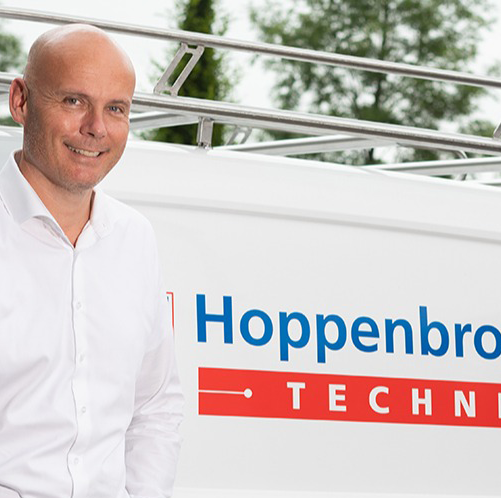 Medewerker staat bij wit busje van Hoppenbrouwers Techniek