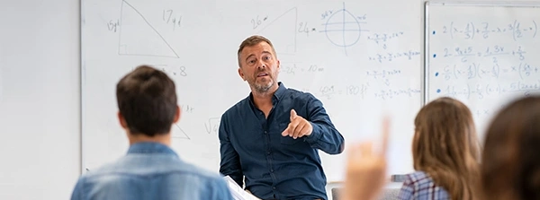 Docent voor een whiteboard geeft les aan studenten in een klaslokaal
