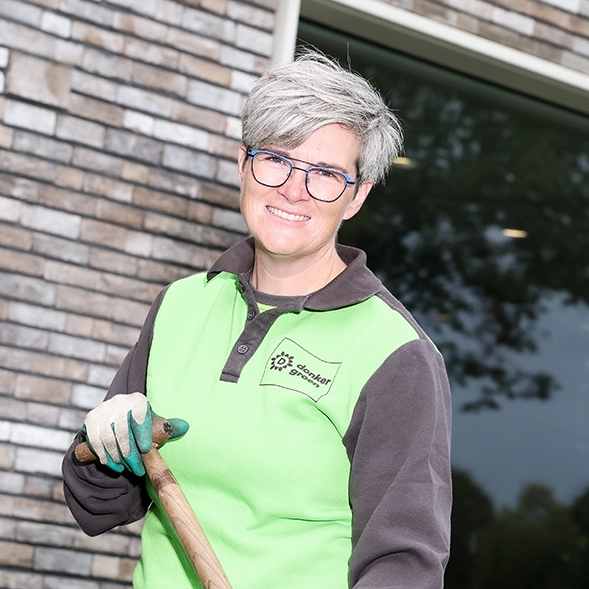 Vrouw in werkkleding en tuinhandschoenen als hovenier.