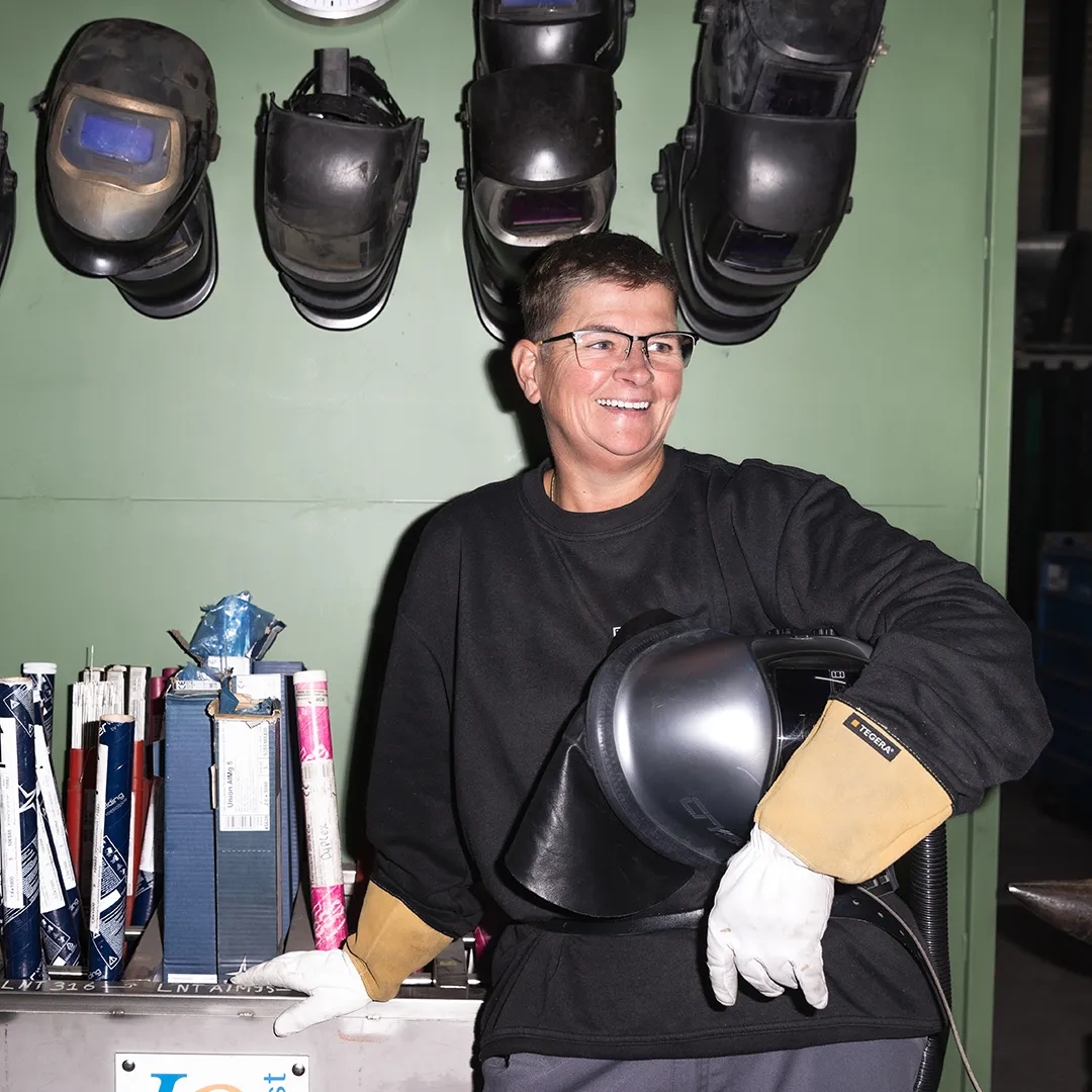 Deelnemer in werkplaats met laskap en beschermende handschoenen, omscholing naar lasser