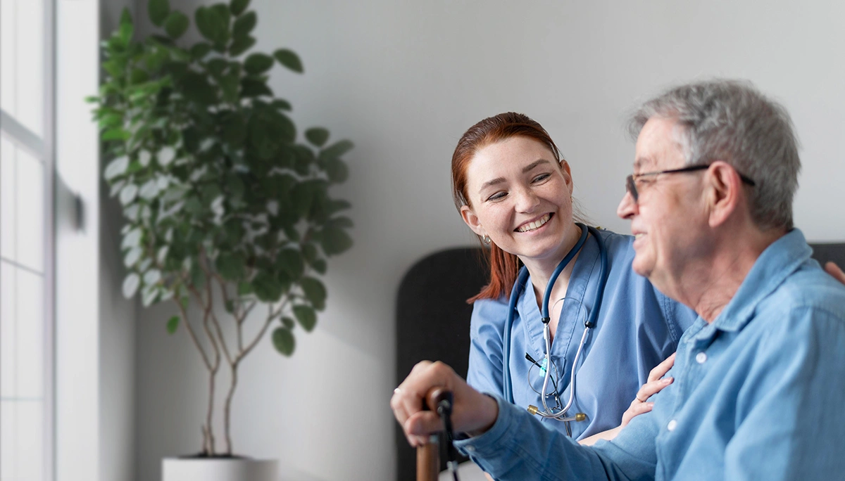 Zorgmedewerker voert een gesprek met een oudere cliënt in een zorginstelling