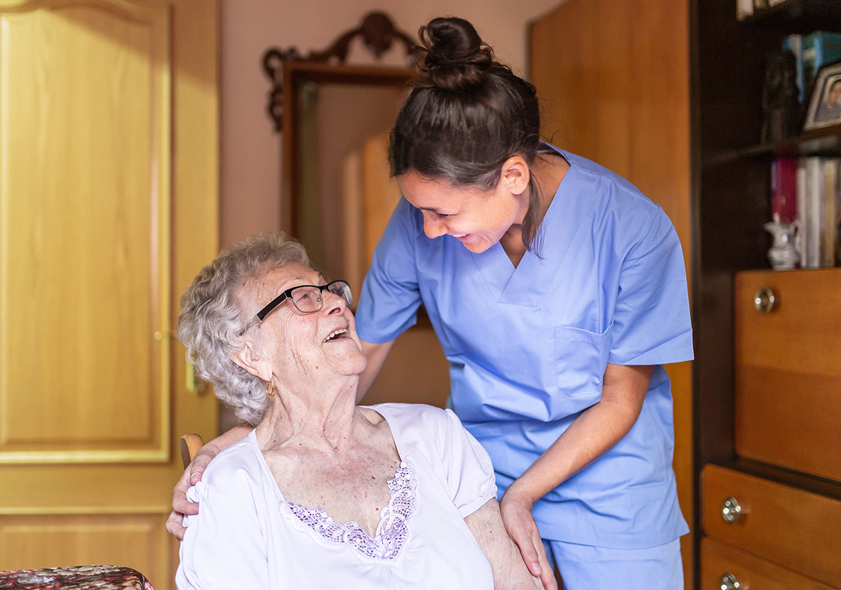 Zorgverlener helpt een oudere vrouw met dagelijkse zorg in een huiselijke omgeving